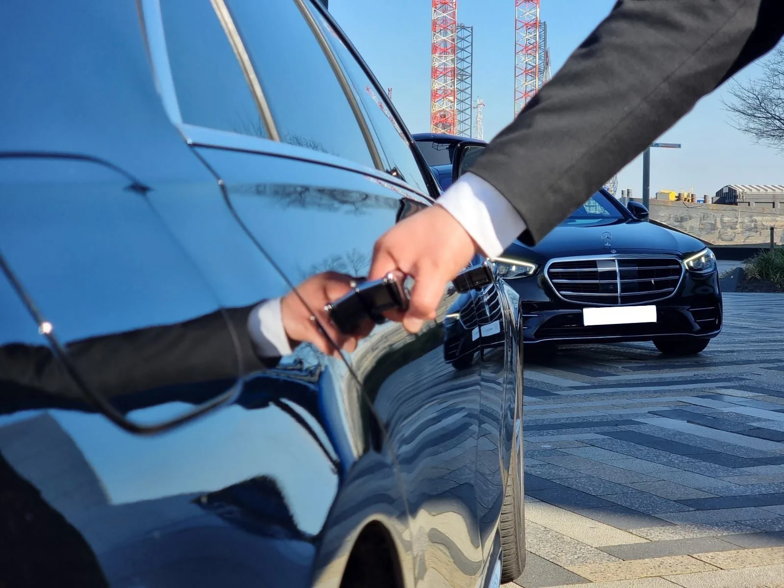 Chauffeur in pak opent de deur van een zwarte Mercedes S-Class