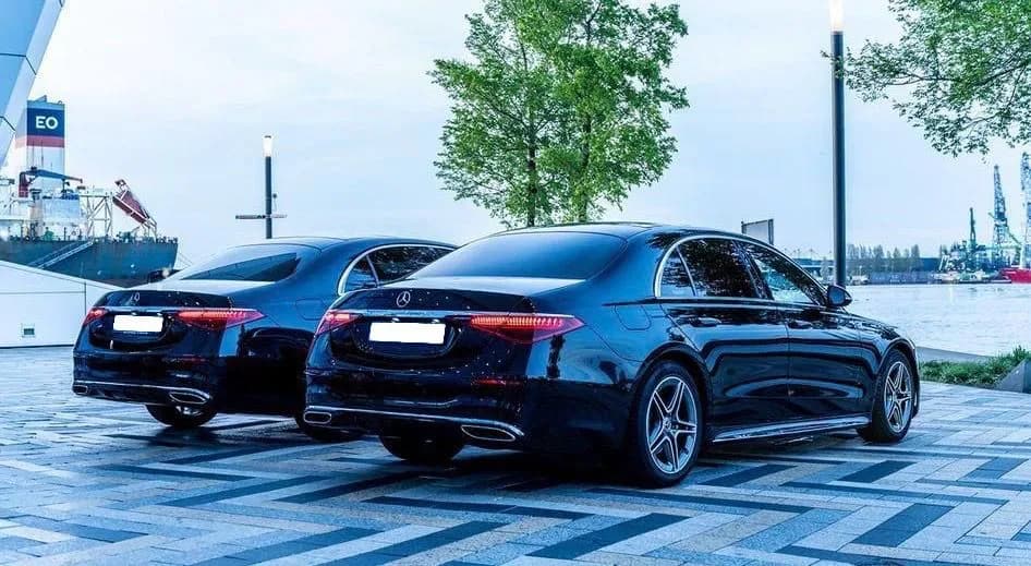 Two black Mercedes S-Class by the water at dusk