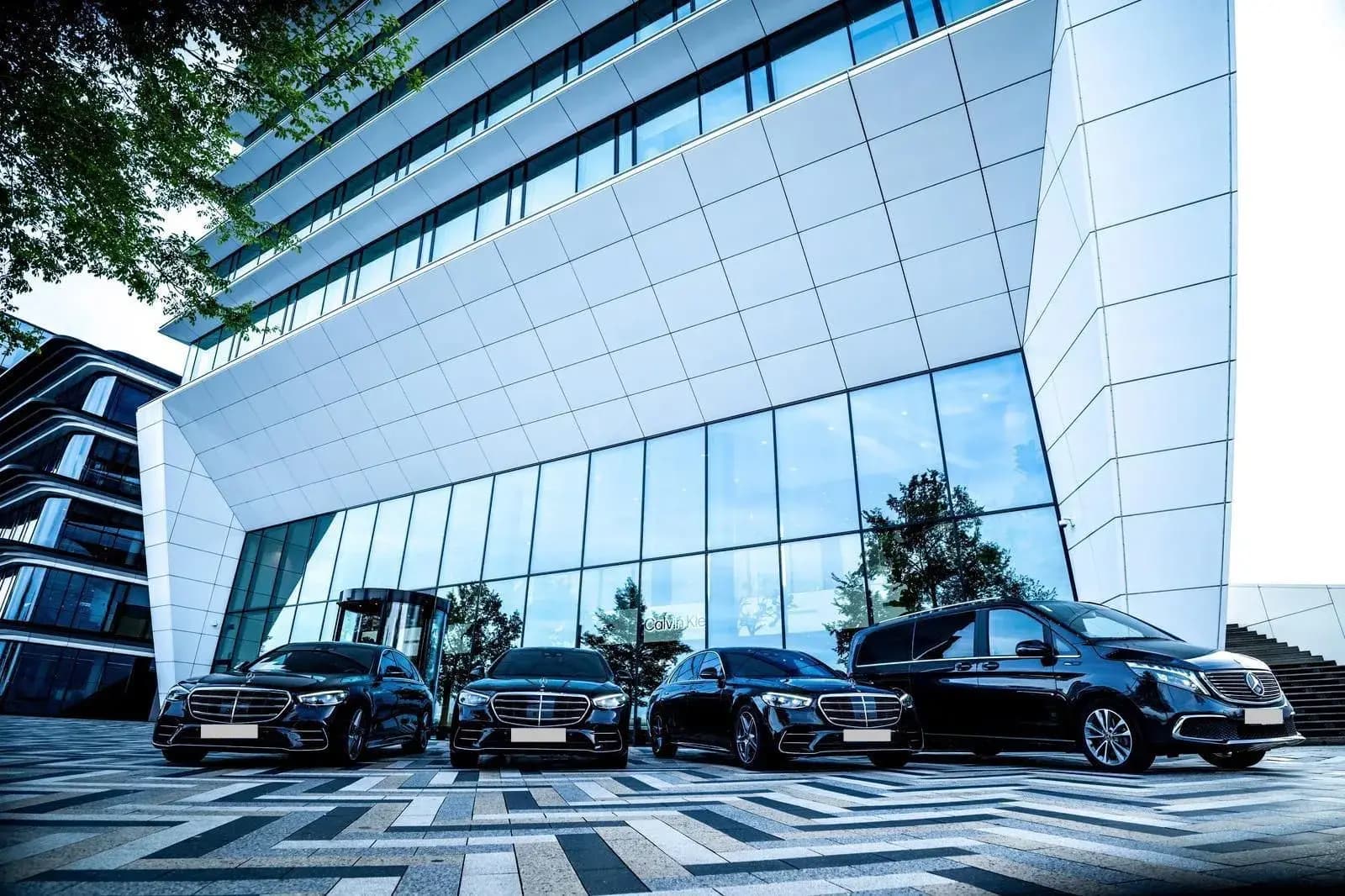 Mercedes S-Class and V-Class available through SchipholRide, in front of a modern glass office building