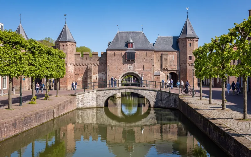 De Koppelpoort in Amersfoort, gezien over het water van de Spui onder een blauwe lucht
