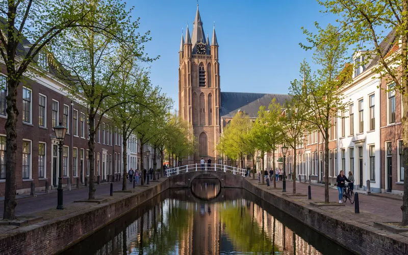 De Oude Delft in Delft met de scheve toren van de Oude Kerk onder een blauwe lucht