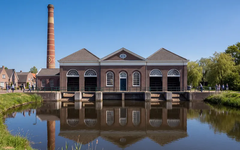 Het stoomgemaal van Halfweg aan het water, met de hoge schoorsteen erachter