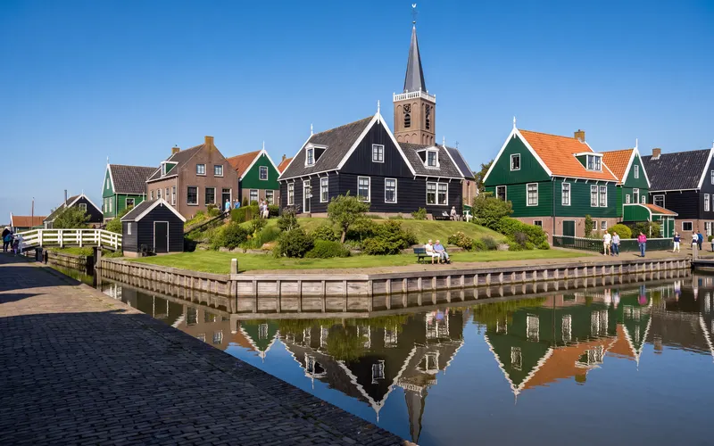 Wooden houses in the Kerkbuurt on Marken, with the church tower behind them, seen across the water