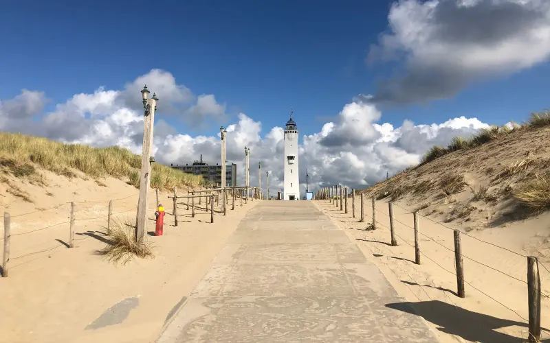 Strandopgang tussen de duinen in Noordwijk, met de witte vuurtoren