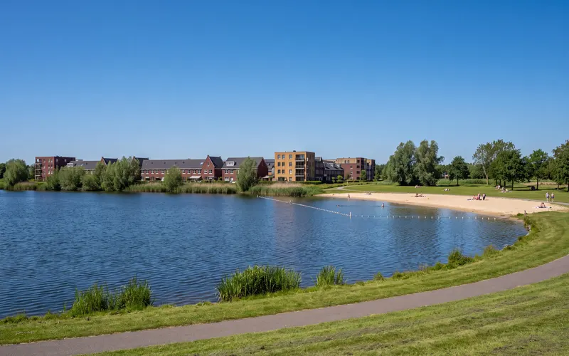 The Westbroekplas lake in Velserbroek, with its sandy beach and houses on the far shore