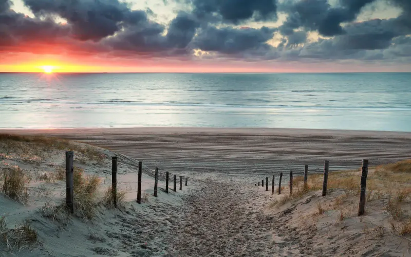 Beach path through the dunes at Zandvoort, with the sun setting over the sea