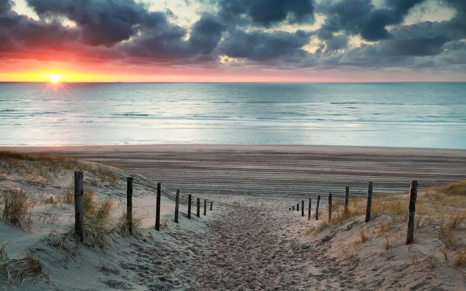 Beach path through the dunes at Zandvoort, with the sun setting over the sea