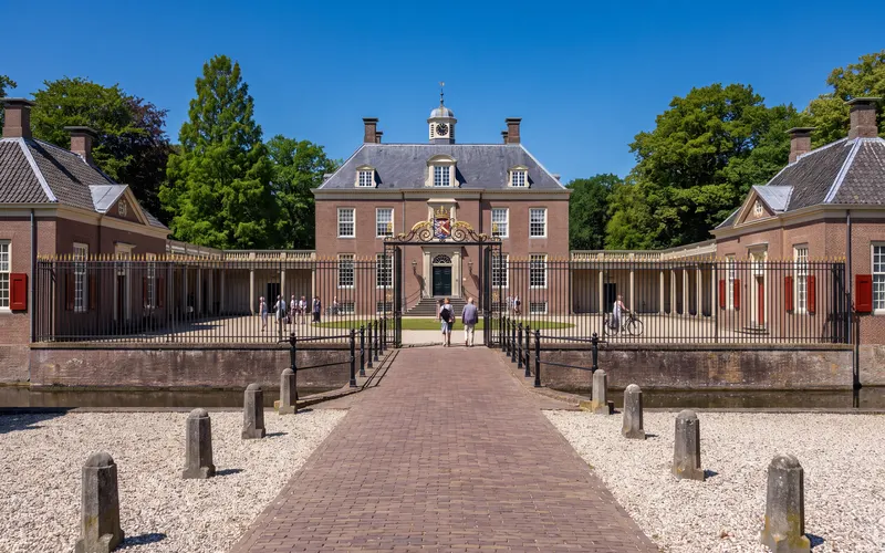 Slot Zeist met de slotgracht en het smeedijzeren toegangshek onder een blauwe lucht