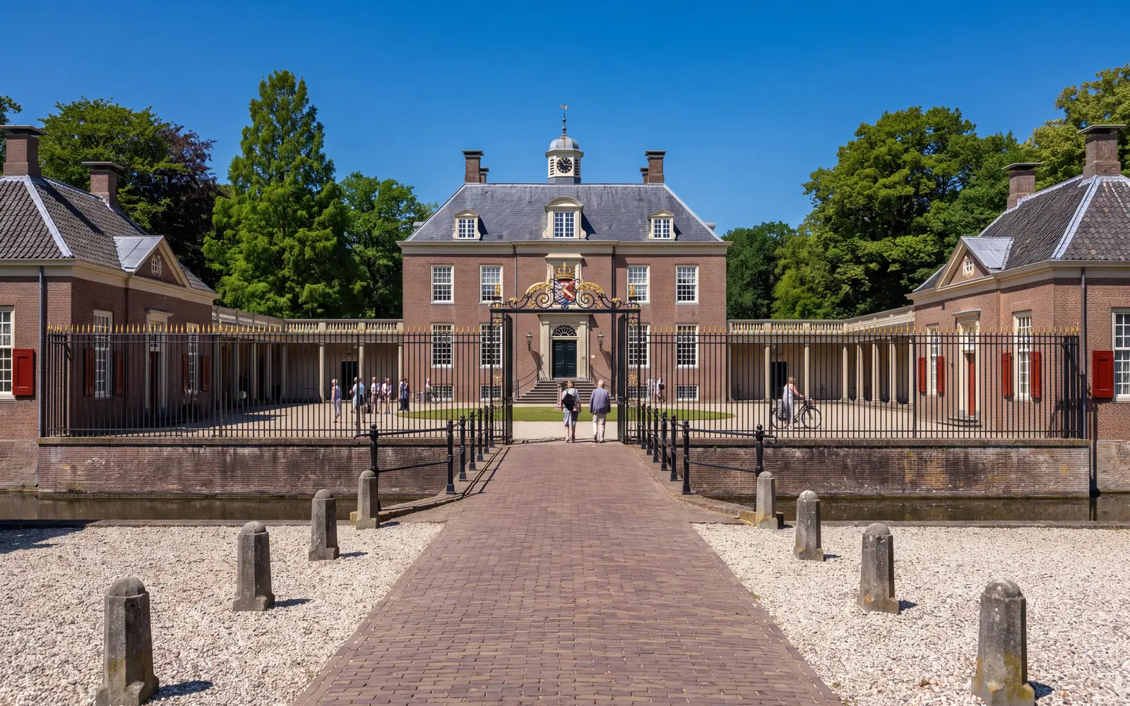 Slot Zeist with its moat and wrought-iron entrance gate under a blue sky