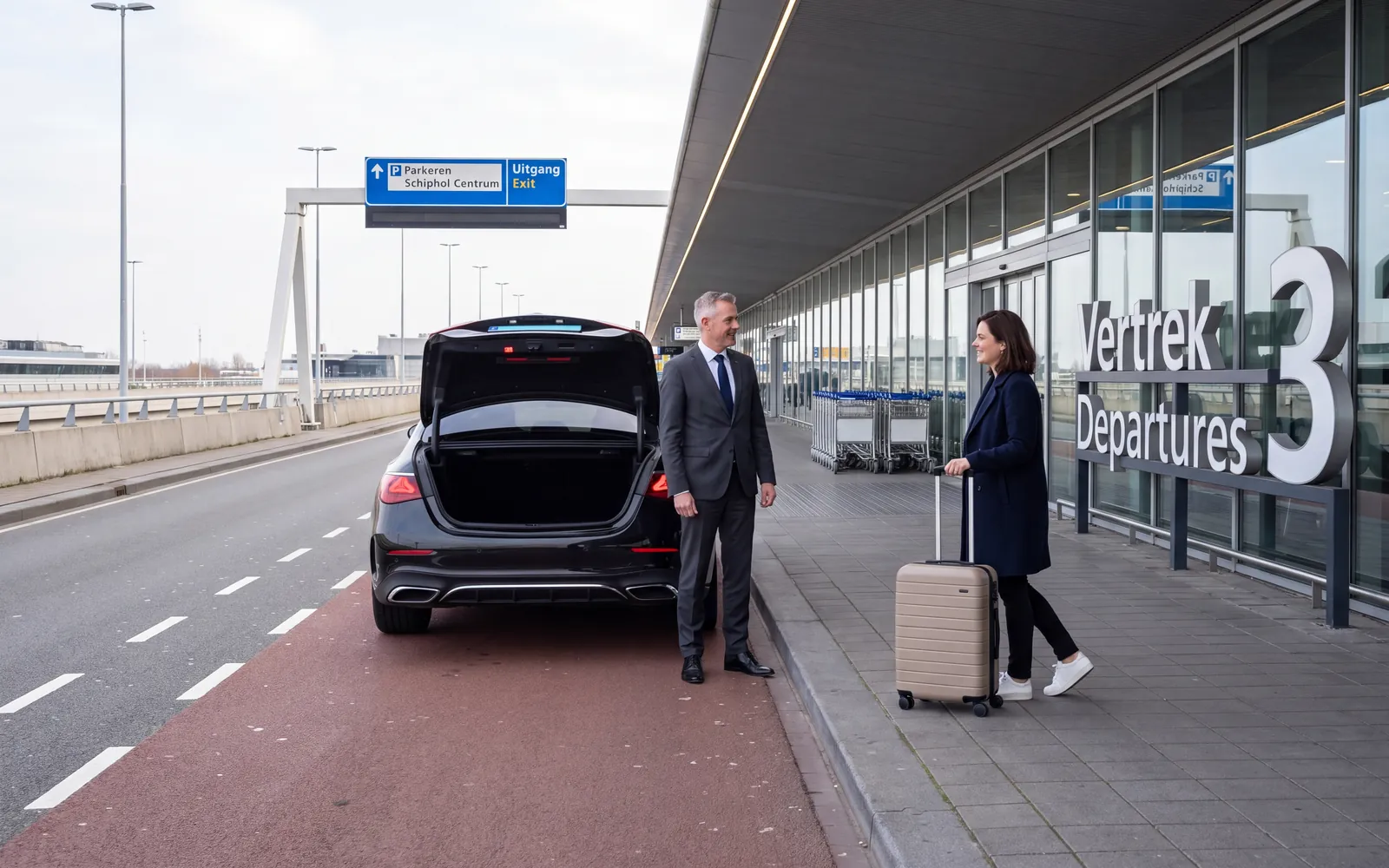 Zwarte sedan met open kofferbak bij Vertrek 3 op Schiphol, de chauffeur en een reiziger met rolkoffer op de stoep