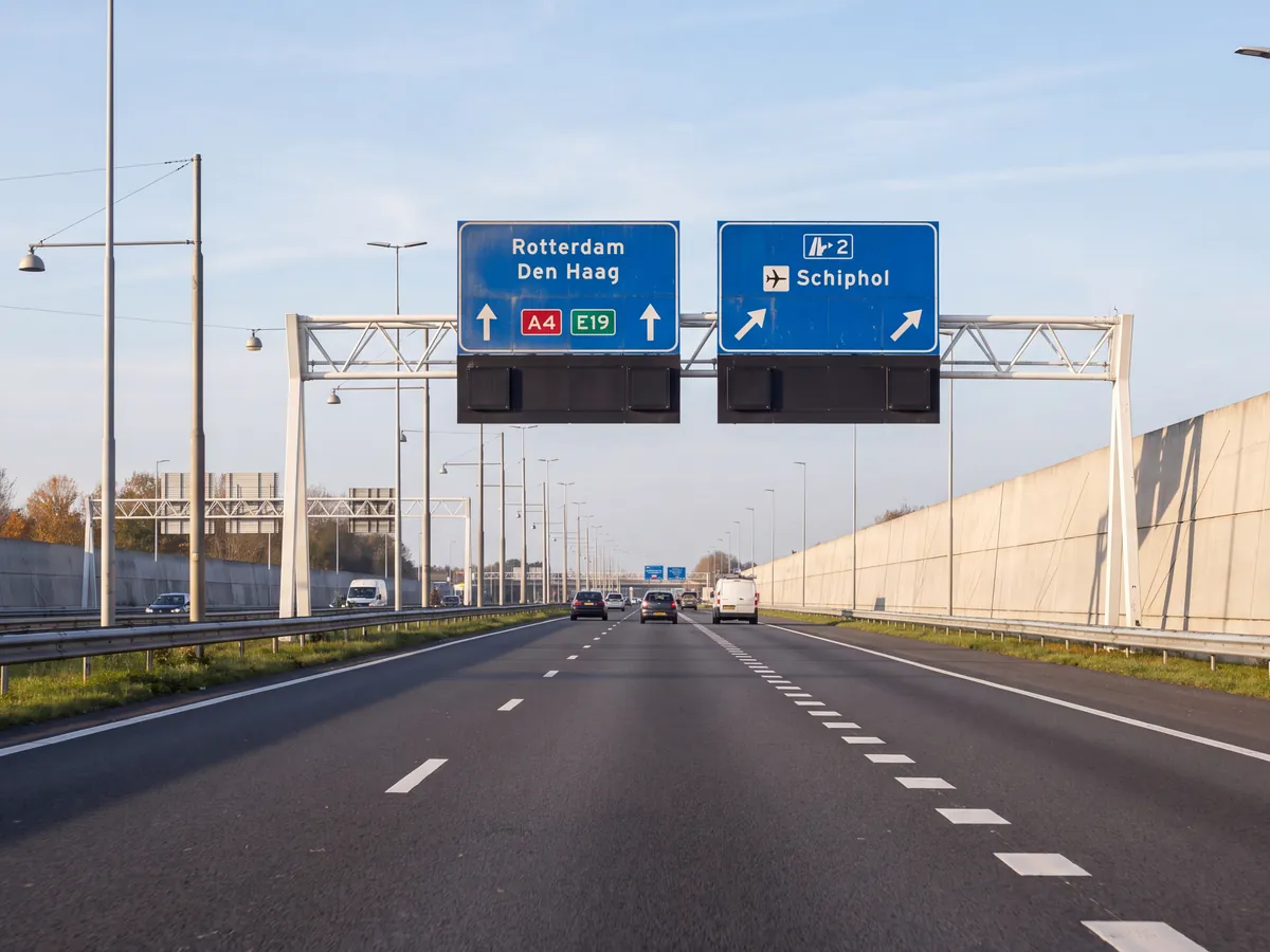 Motorway with blue overhead signs, the right-hand lanes signed for Schiphol